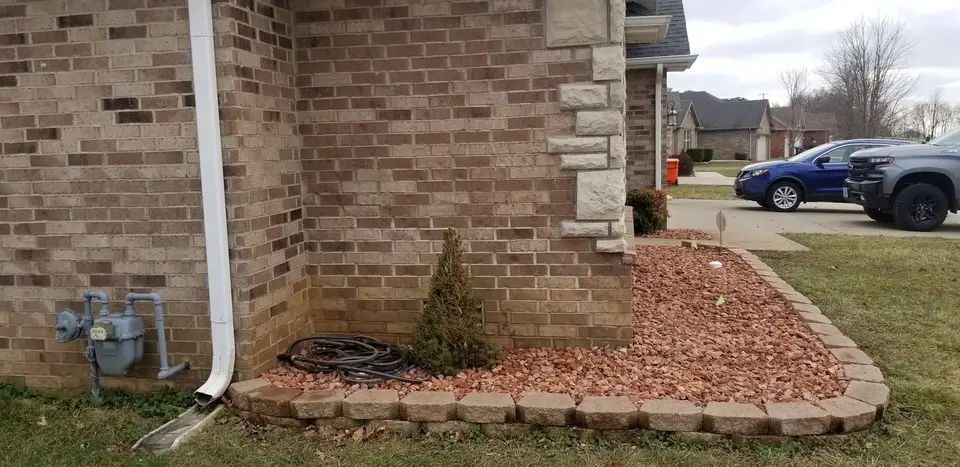 Landscape bed with block edging and mulch along a brick house