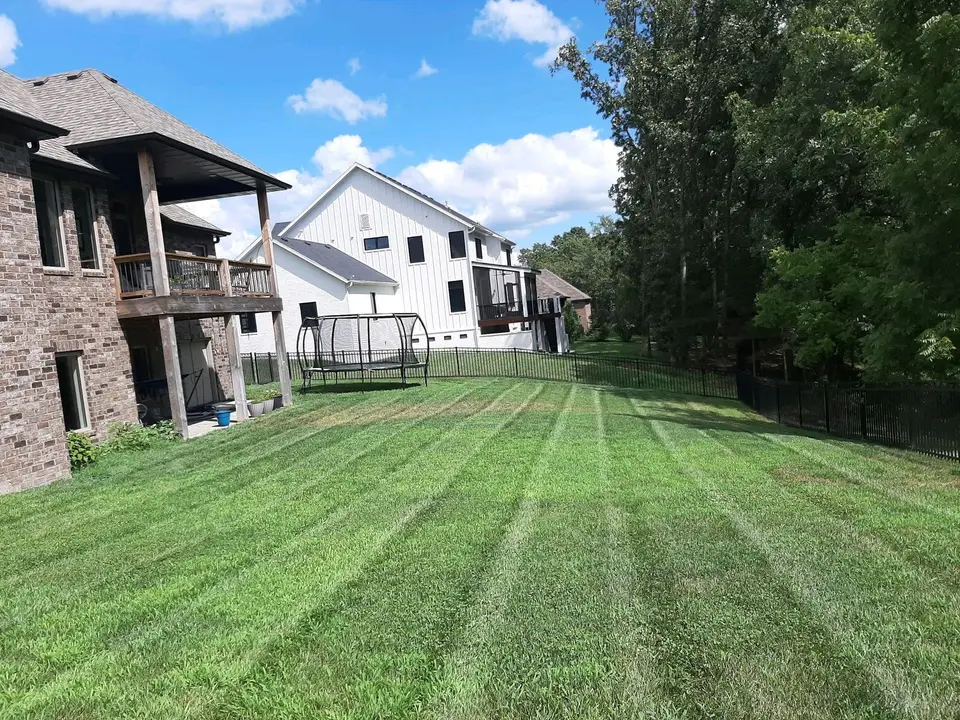 Freshly striped lawn behind a brick home, mowed by L&M Lawncare